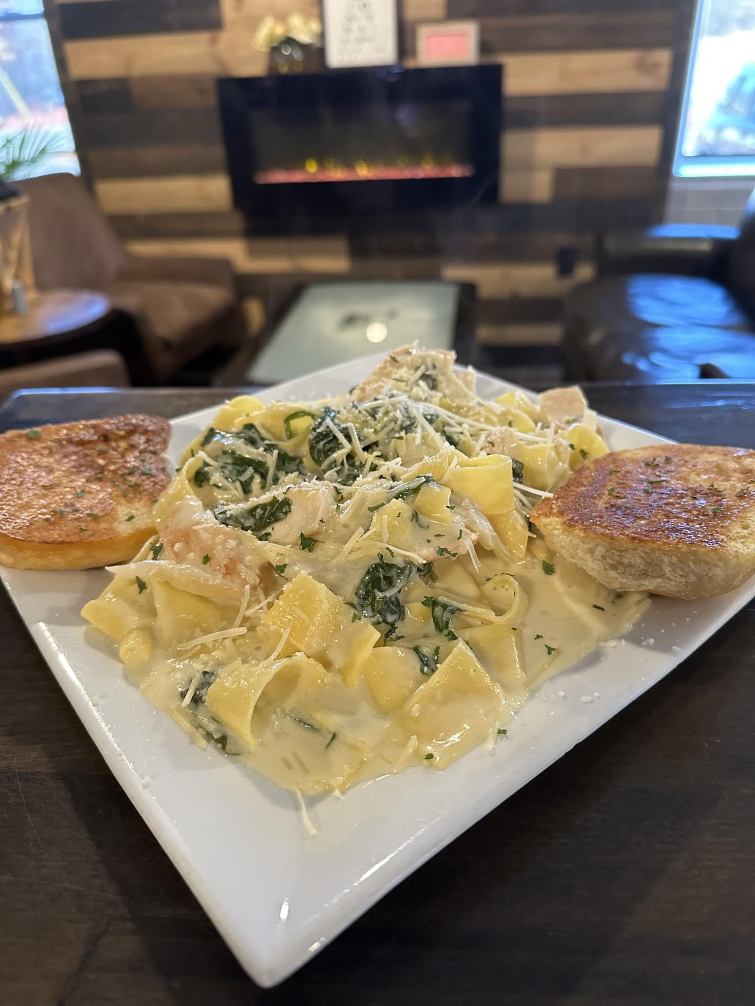 Grilled chicken Florentine served over pappardelle pasta with garlic bread